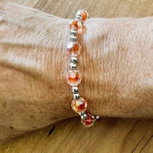 Elastic bead bracelet made by 10yo for school $. Stretchy—orange/silvery.